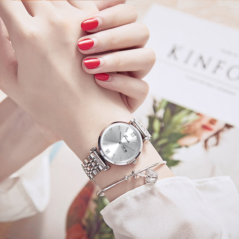 Silver women's quartz watch with stainless steel strap on wrist, round dial with minimal markings.