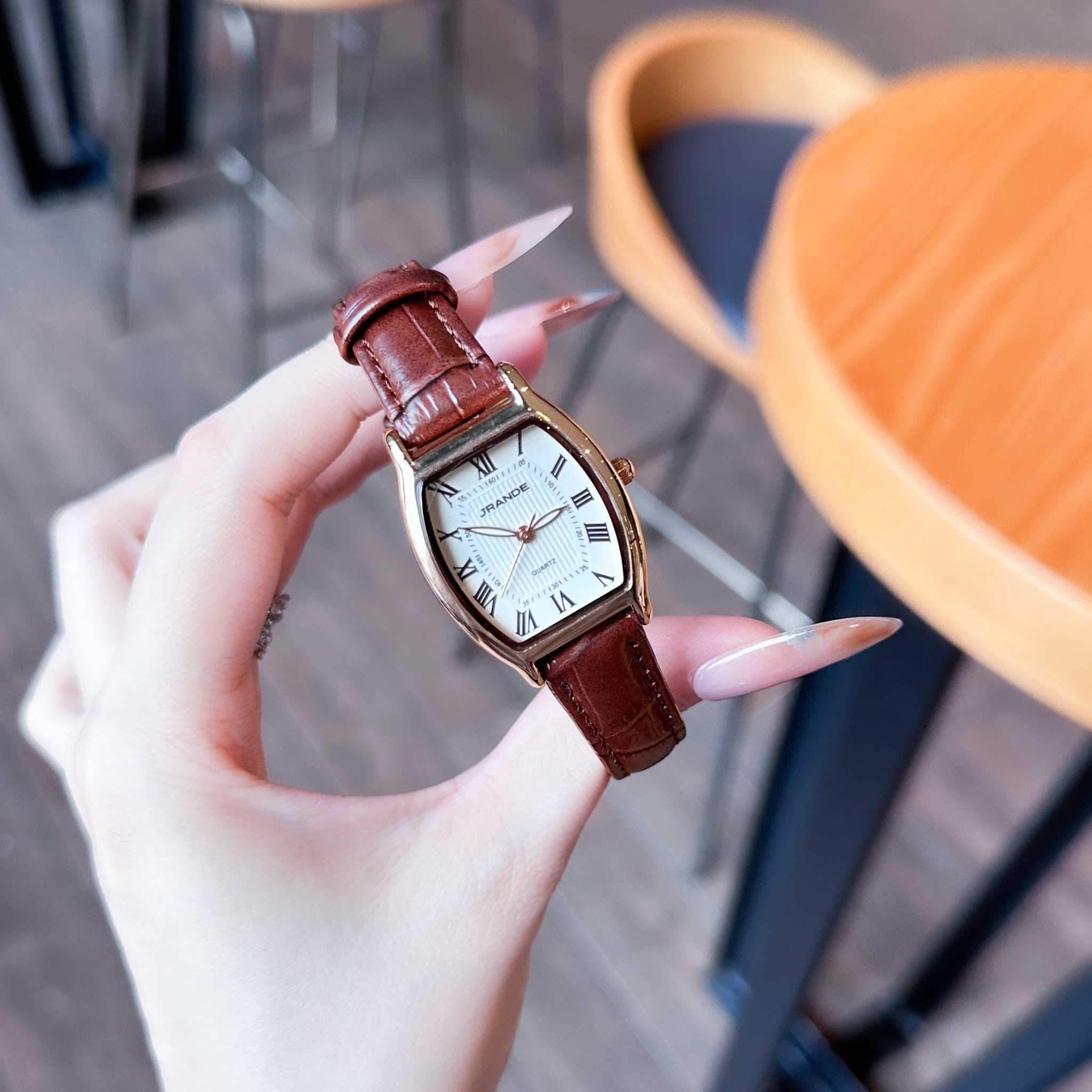 Women's quartz watch with bronze-tone case, white dial, and brown leather strap.