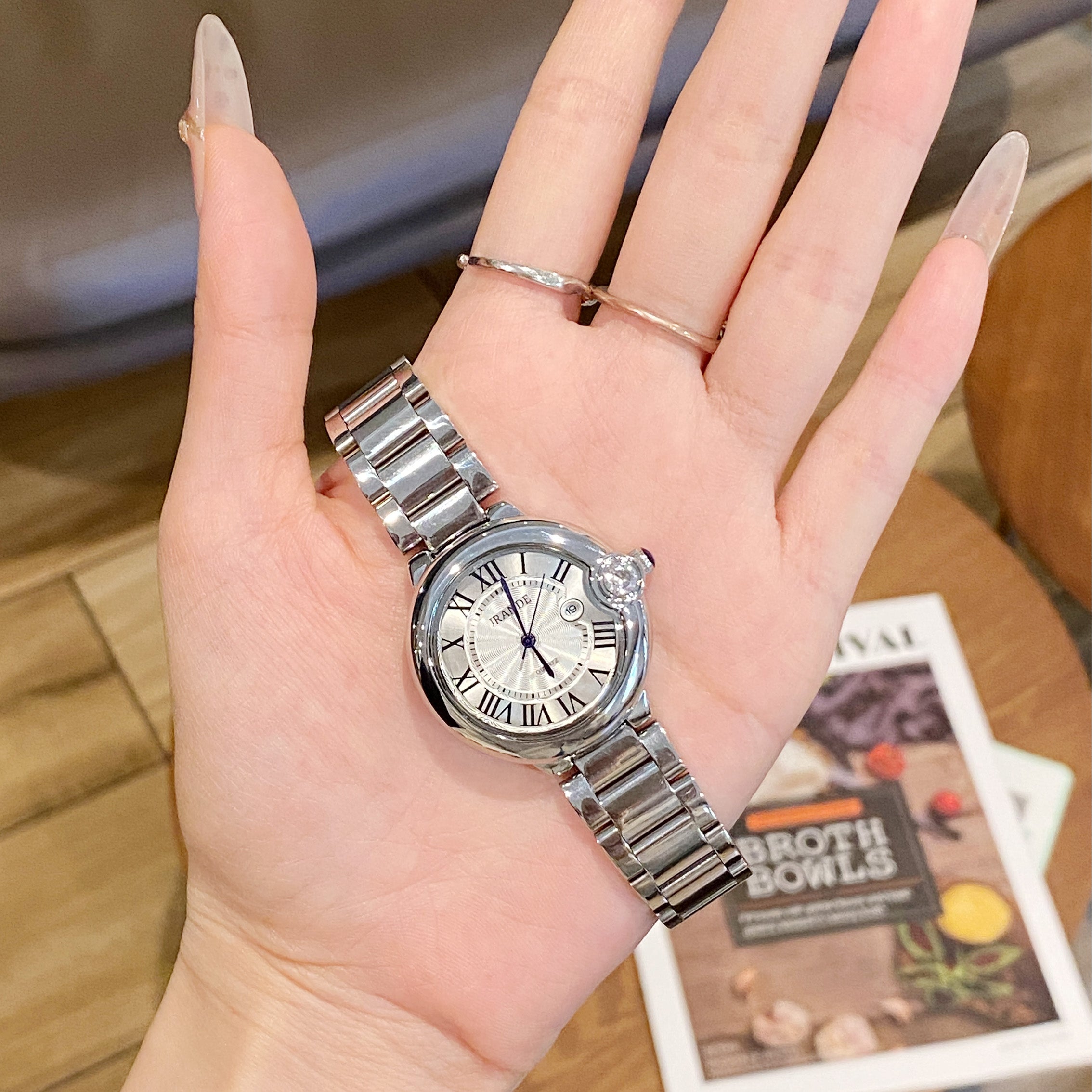 Silver stainless steel women's quartz watch with white dial and Roman numerals on wrist.
