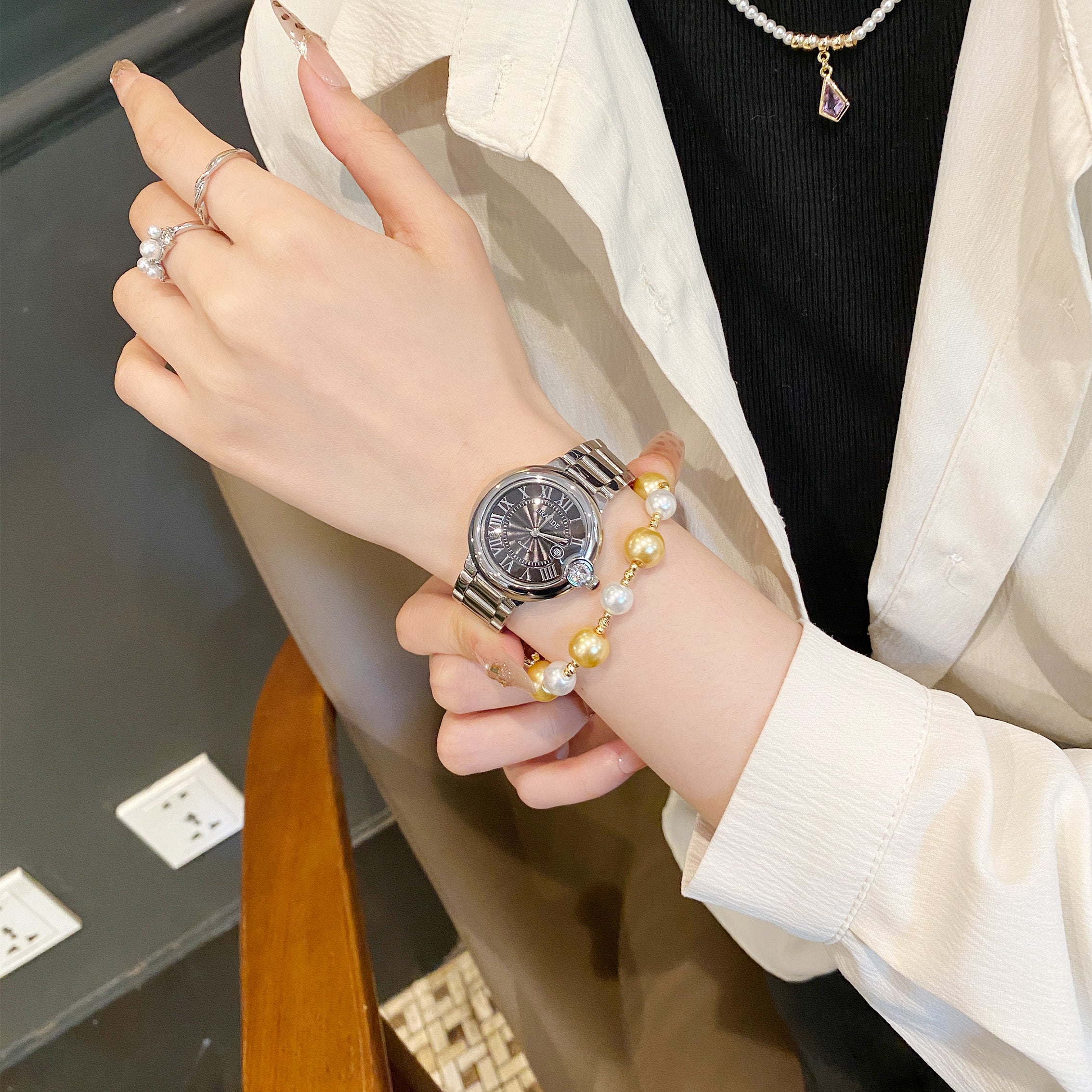 Women's stainless steel quartz watch with black dial and silver bracelet band, water resistant design.